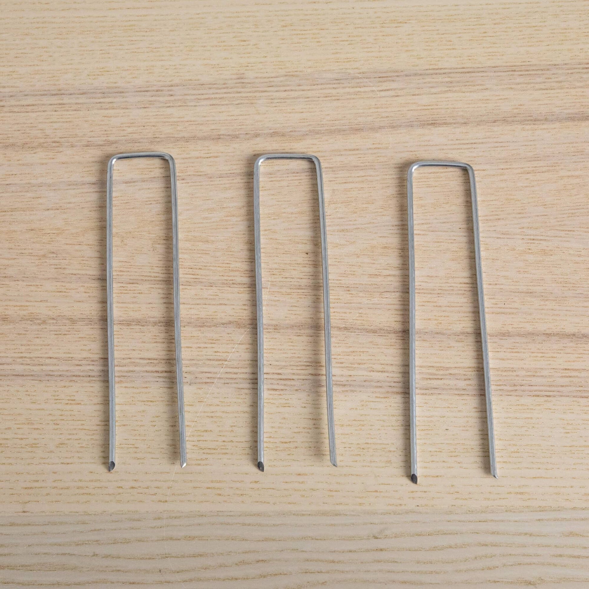 4-pack silver metal U-shaped plant stakes on light wood surface on Tampa Home & Garden Store