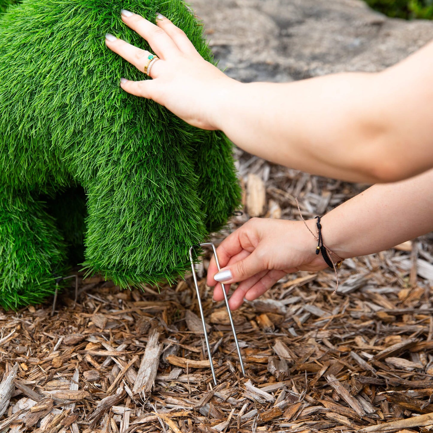 18in UV-resistant artificial grass topiary ball with green blades being shaped by hands on Tampa Home & Garden Store