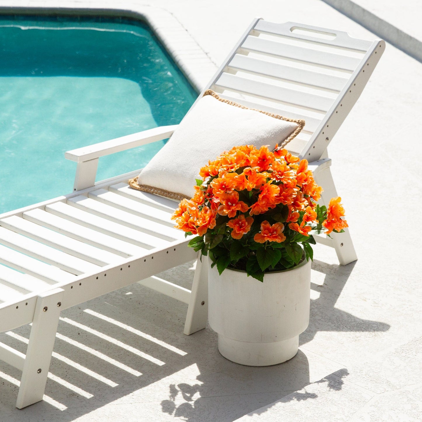 Artificial azalea bush with orange blooms in white pot on poolside lounge chair on Tampa Home & Garden Store