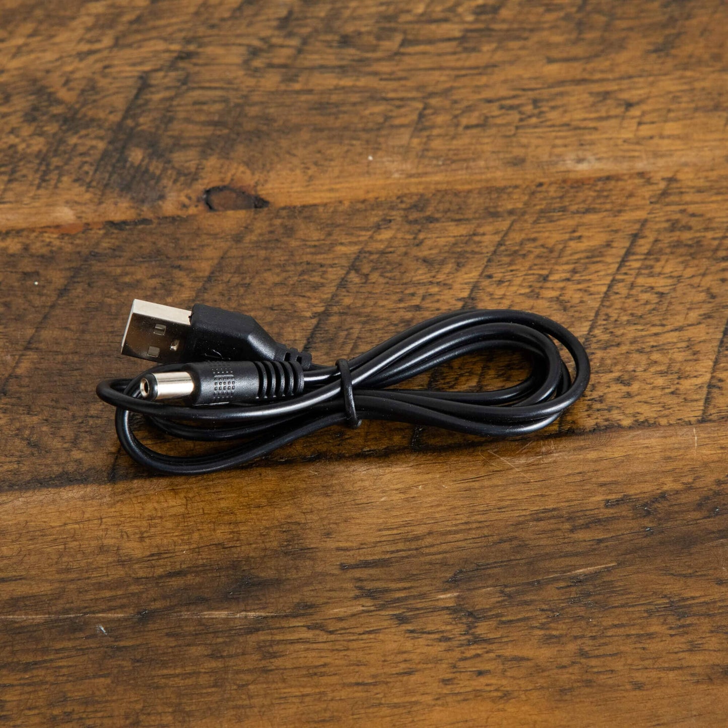USB power cable with USB-A plug and barrel connector coiled on a wooden surface on Tampa Home & Garden Store