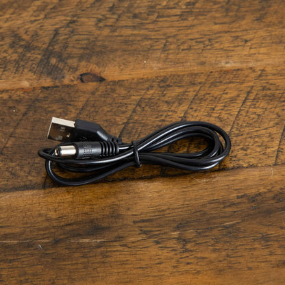 USB power cable with USB-A plug and barrel connector coiled on a wooden surface on Tampa Home & Garden Store