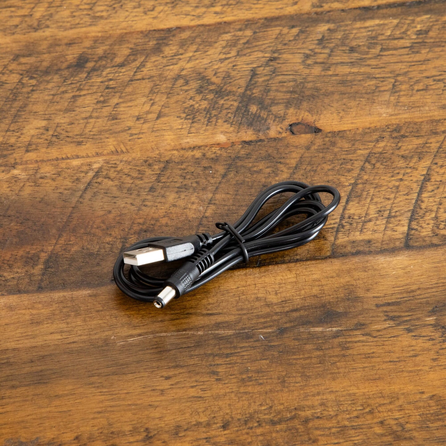 Coiled black USB power cord for Nearly Natural Autumn Maple tree lighting on rustic wood surface on Tampa Home & Garden Store