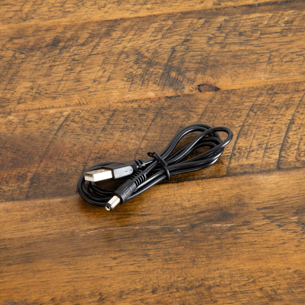 Coiled black USB power cord for Nearly Natural Autumn Maple tree lighting on rustic wood surface on Tampa Home & Garden Store
