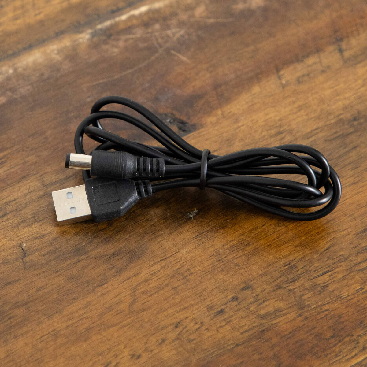 Black USB power cable with USB-A connector coiled on a wooden surface on Tampa Home & Garden Store
