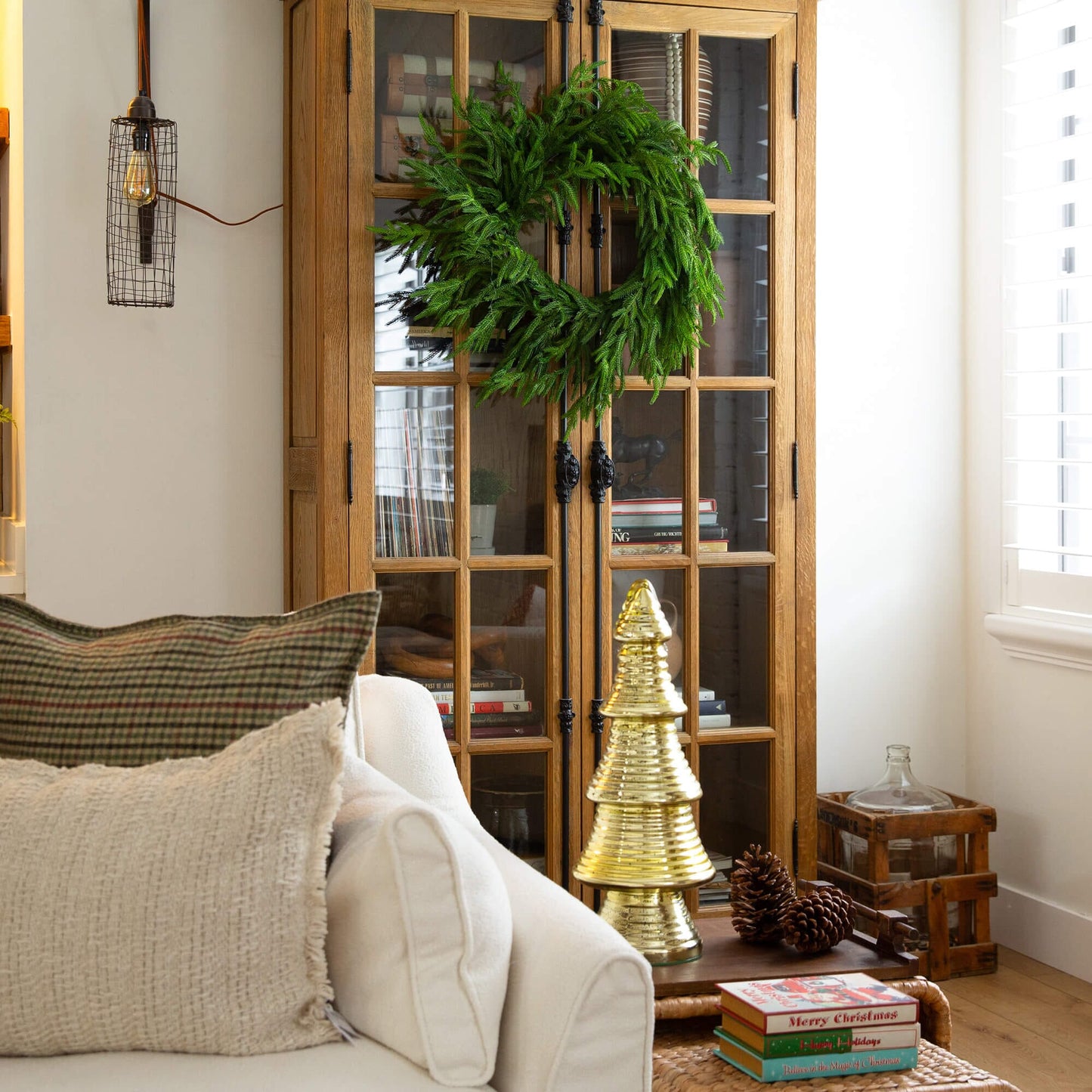 24-inch Nearly Natural artificial Norfolk Island Pine wreath with natural look displayed on a wooden glass-front cabinet on Tampa Home & Garden Store