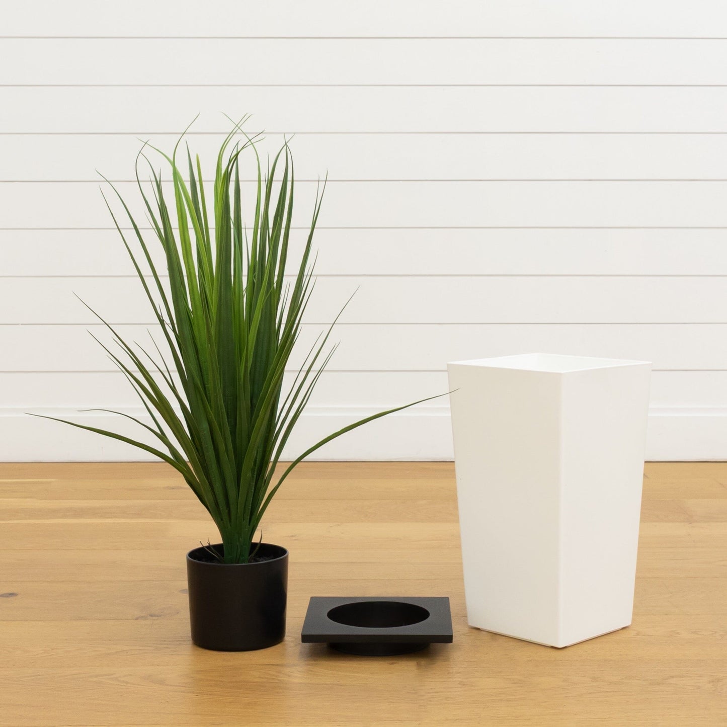 3 ft artificial grass plant in a black pot with long green blades beside a white tower planter on Tampa Home & Garden Store