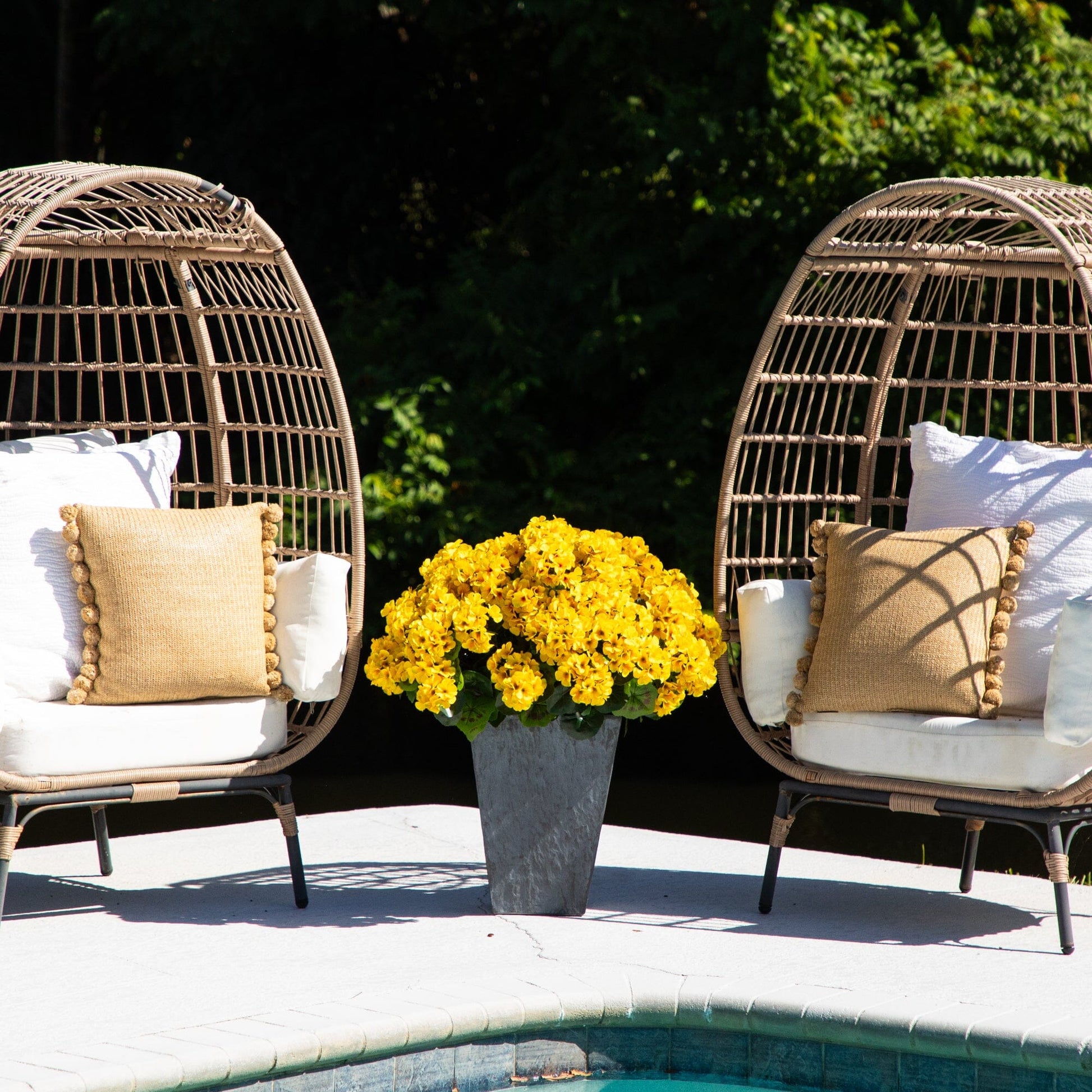 Artificial geranium plant in slate ceramic planter between wicker chairs with beige cushions on Tampa Home & Garden Store