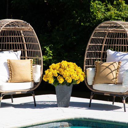 Artificial geranium plant in slate ceramic planter between wicker chairs with beige cushions on Tampa Home & Garden Store