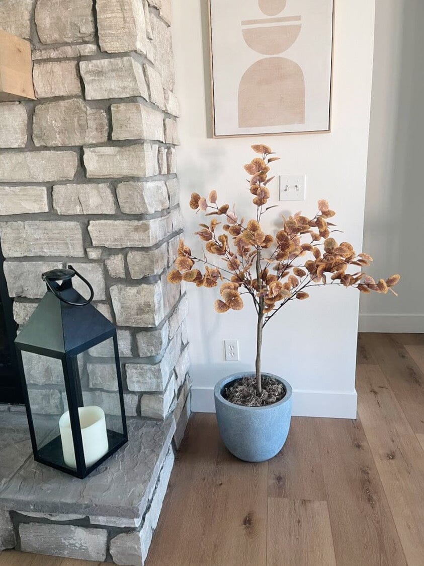 4’ Autumn Eucalyptus Artificial Tree in blue pot with brown-orange leaves inside by hearth on Tampa Home & Garden Store