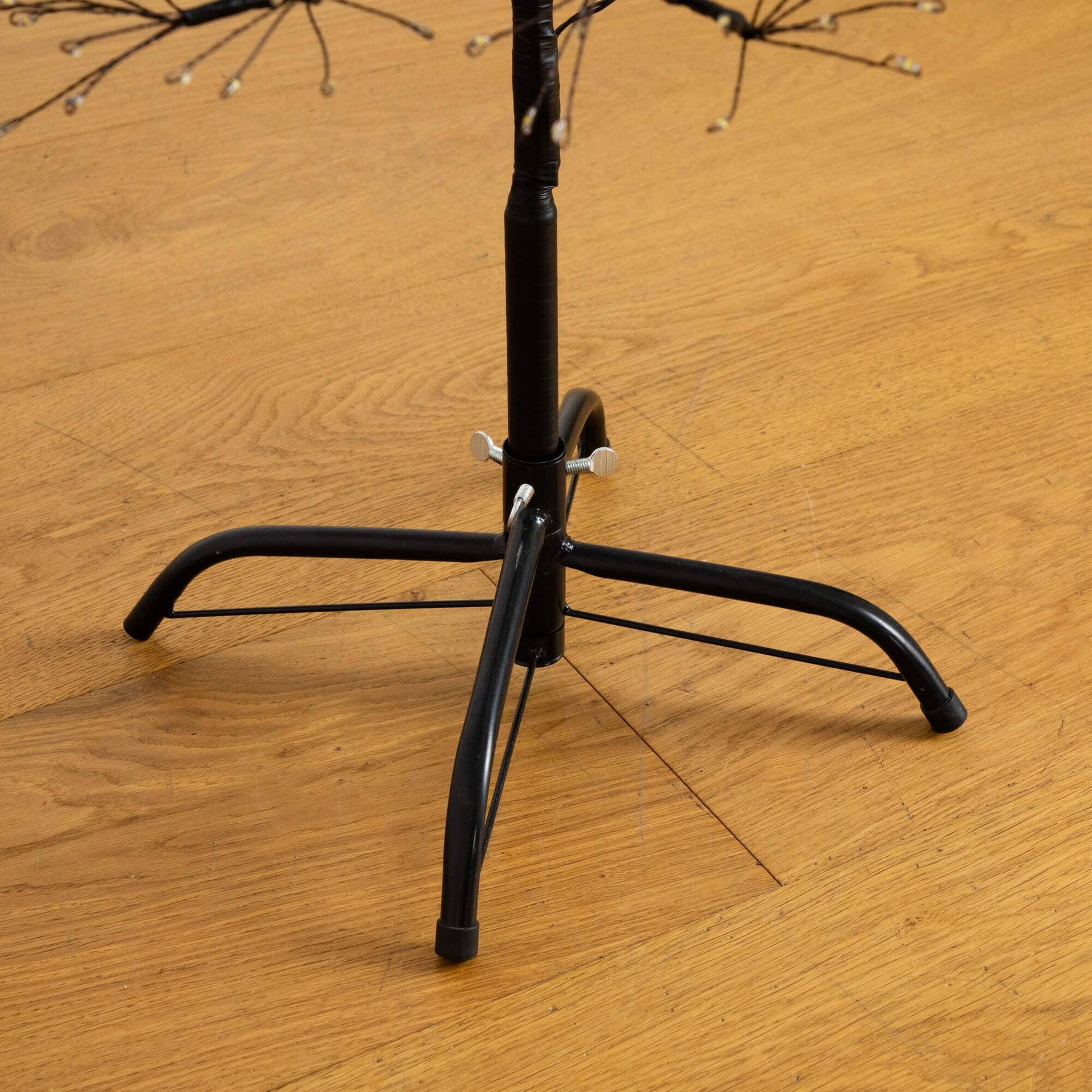 Black metal tree stand base for 4' pre-lit Halloween starburst tree on wood floor on Tampa Home & Garden Store