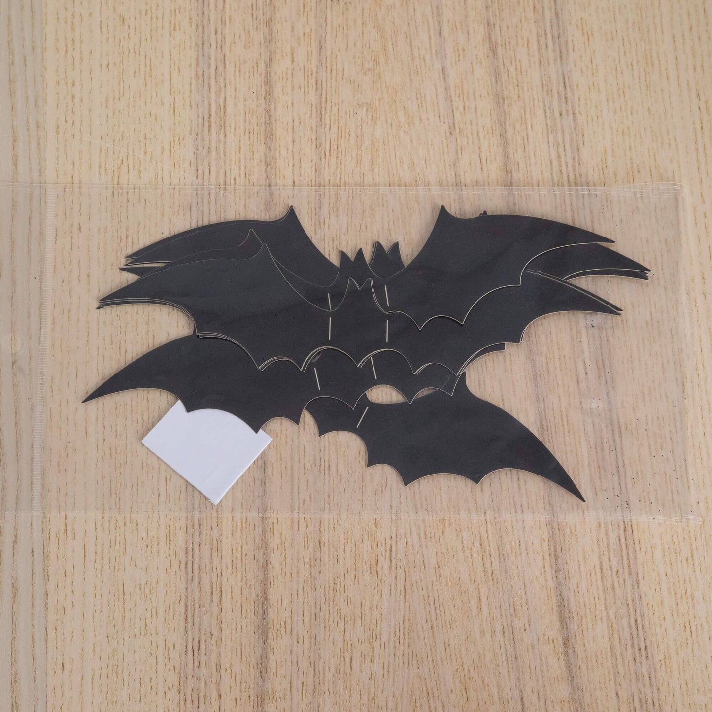 Black Halloween bat cutouts on a light wood surface with a white tag on Tampa Home & Garden Store