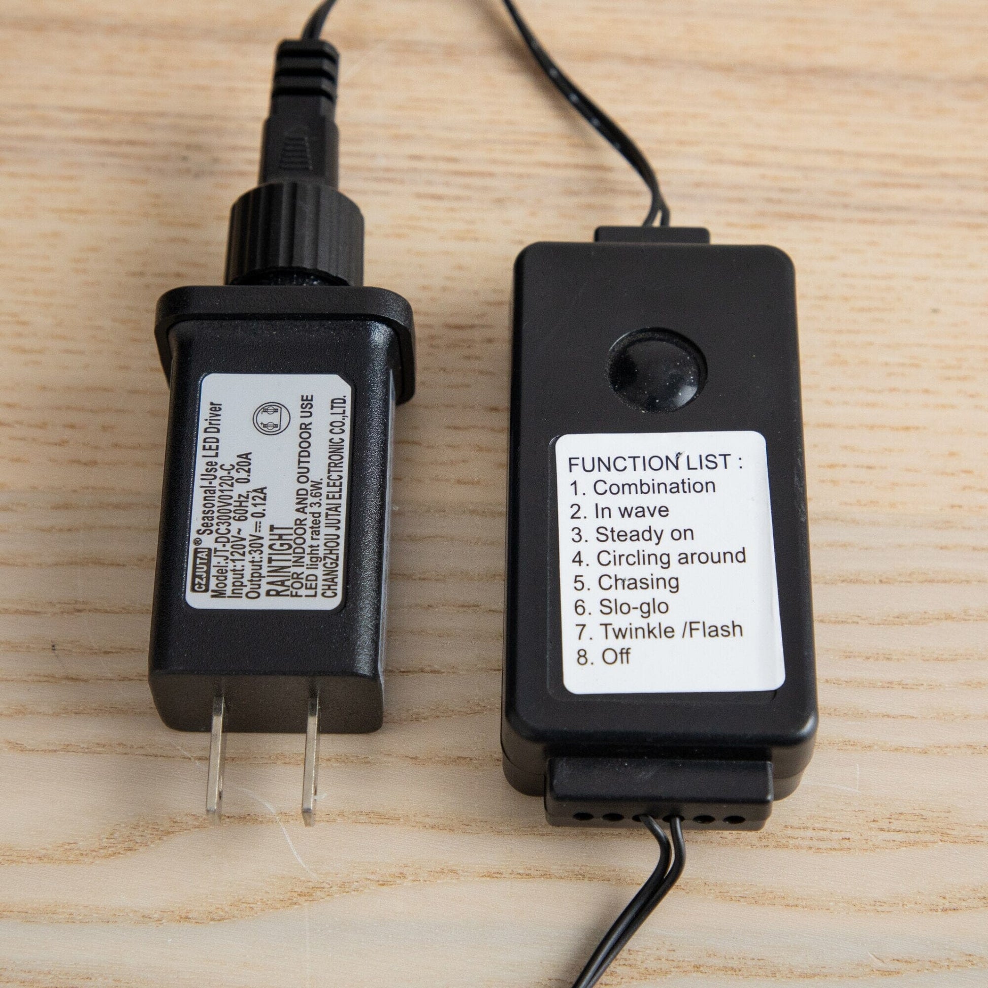 Two black power adapters with white labels and cords on a wooden surface on Tampa Home & Garden Store