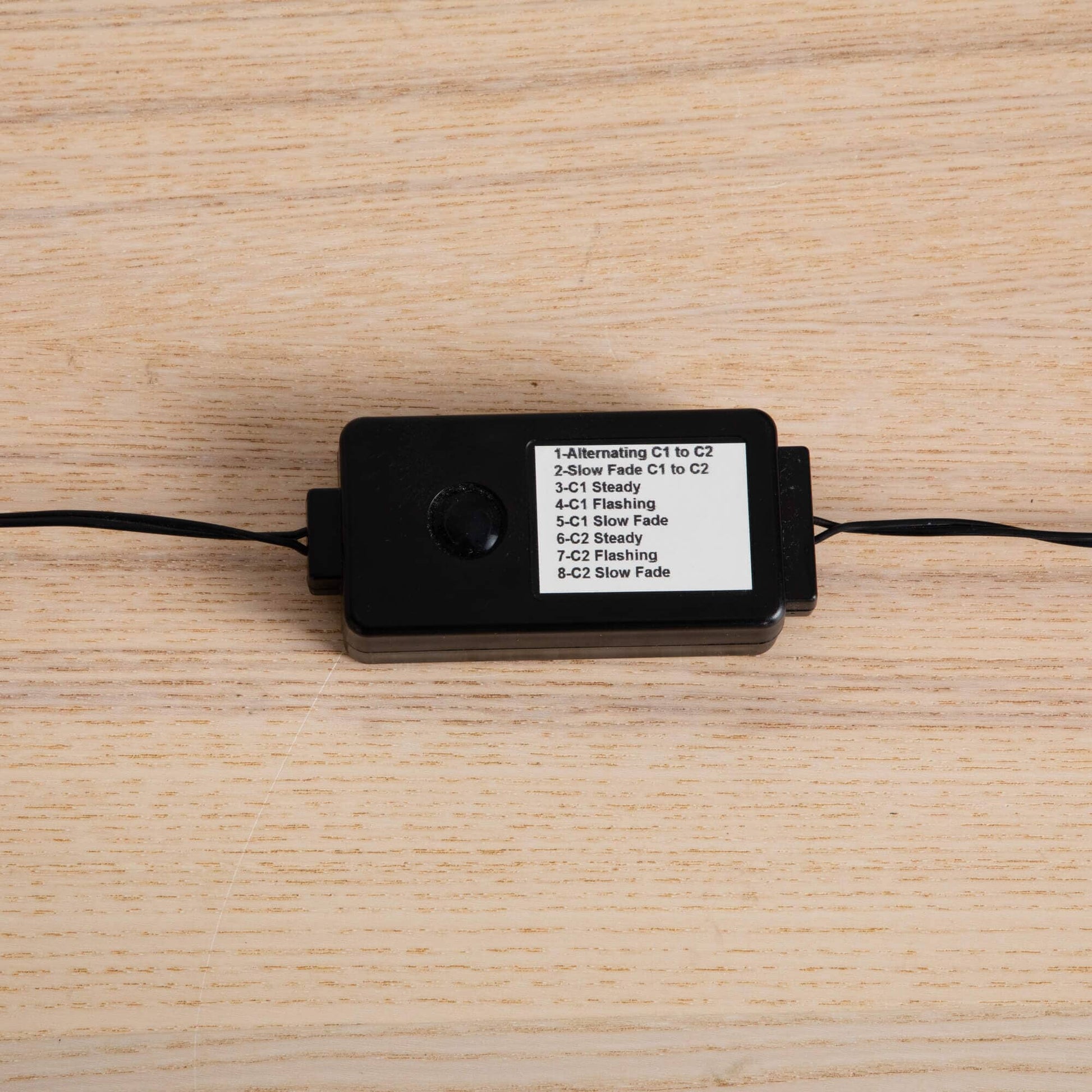 LED light controller for a pre-lit Halloween tree, black box with mode list on wood surface on Tampa Home & Garden Store