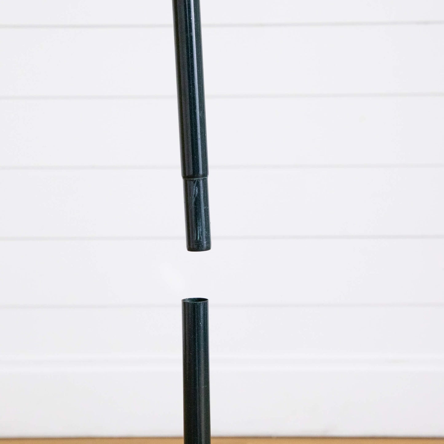 Black metal central pole from a pop up Christmas tree stand against a white panel backdrop on Tampa Home & Garden Store