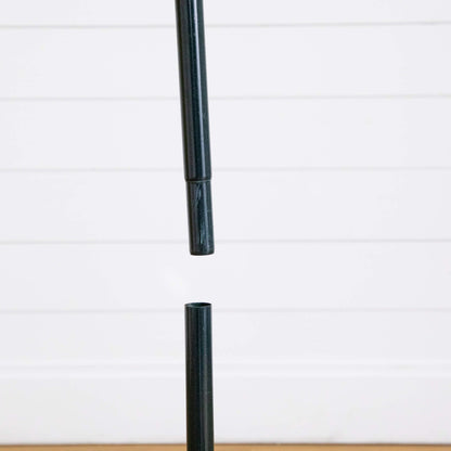 Black metal central pole from a pop up Christmas tree stand against a white panel backdrop on Tampa Home & Garden Store