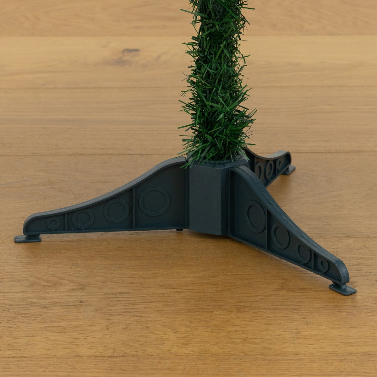 Artificial Christmas tree segment with green pine needles on a gray plastic stand on Tampa Home & Garden Store