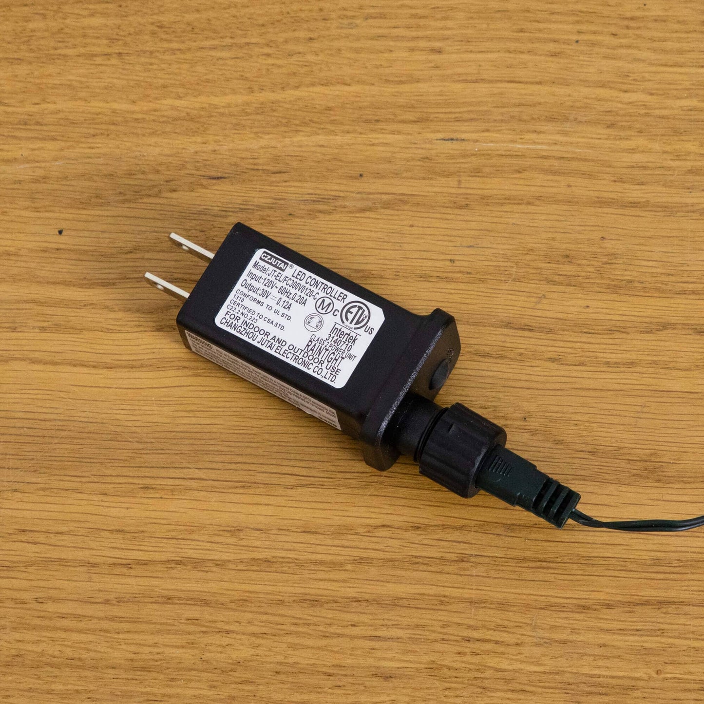 LED controller power adapter, black rectangular unit with label and two-prong plug on wood on Tampa Home & Garden Store