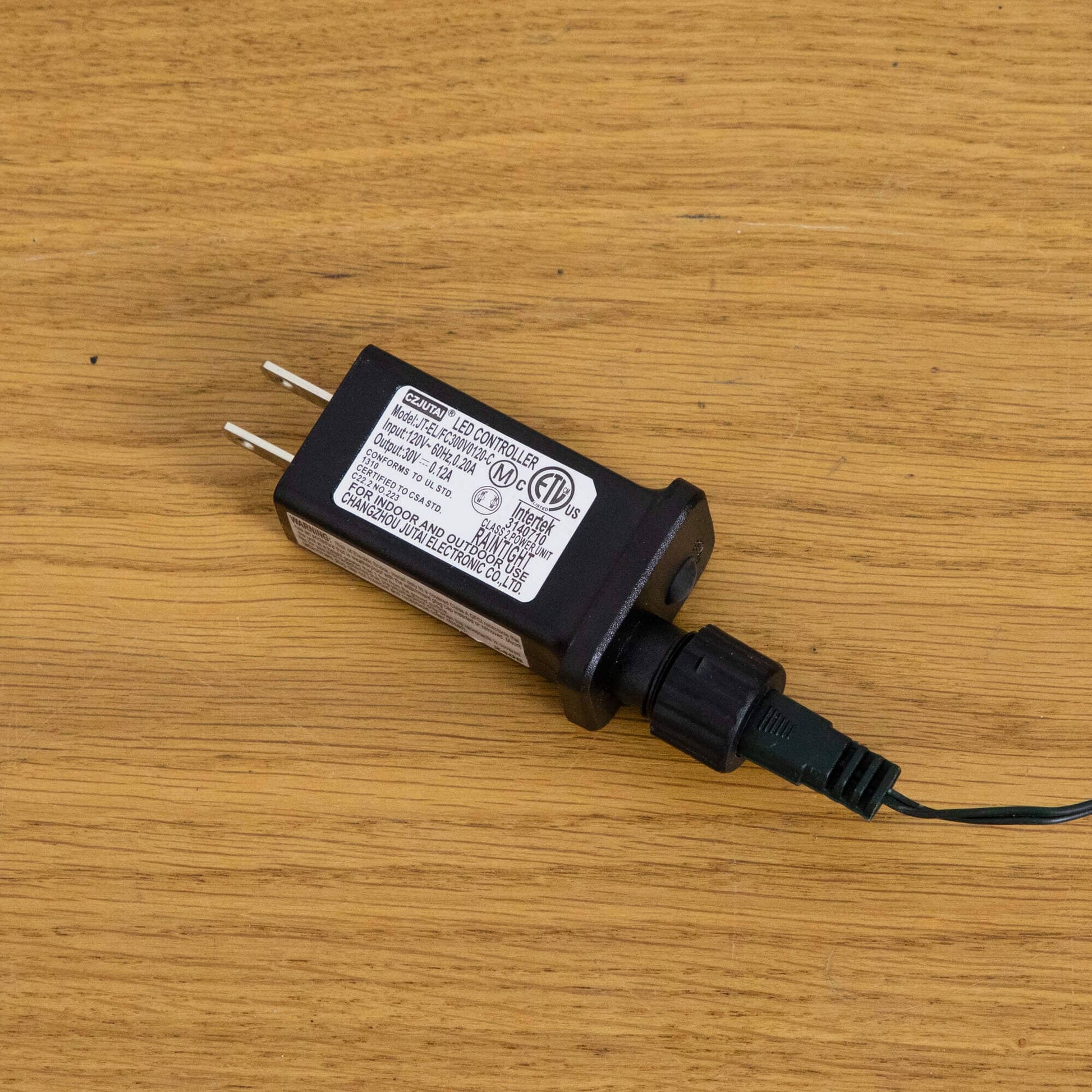LED controller power adapter, black rectangular unit with label and two-prong plug on wood on Tampa Home & Garden Store