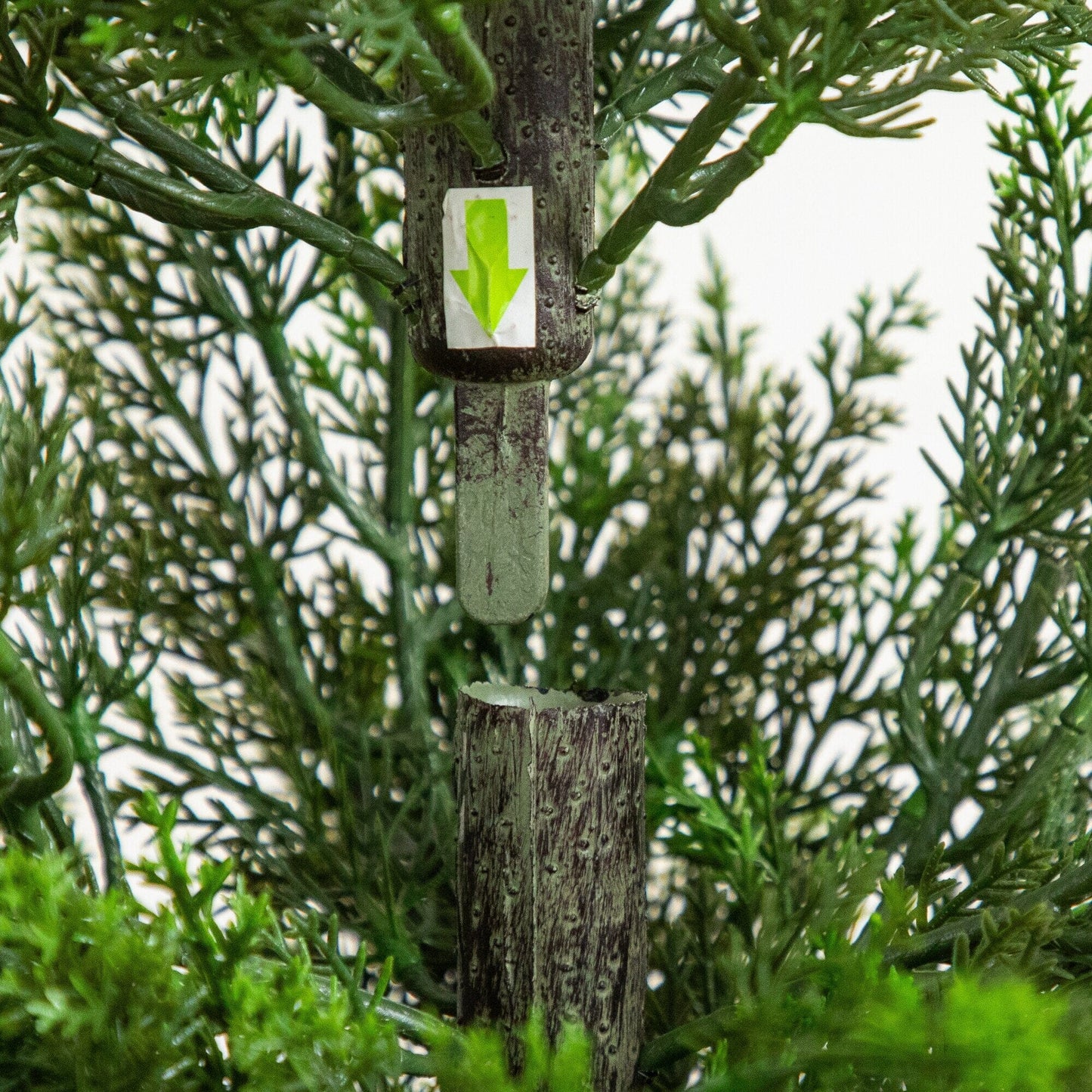 56-inch artificial cedar tree with green fronds and gray trunk; white tag with neon green arrow on Tampa Home & Garden Store