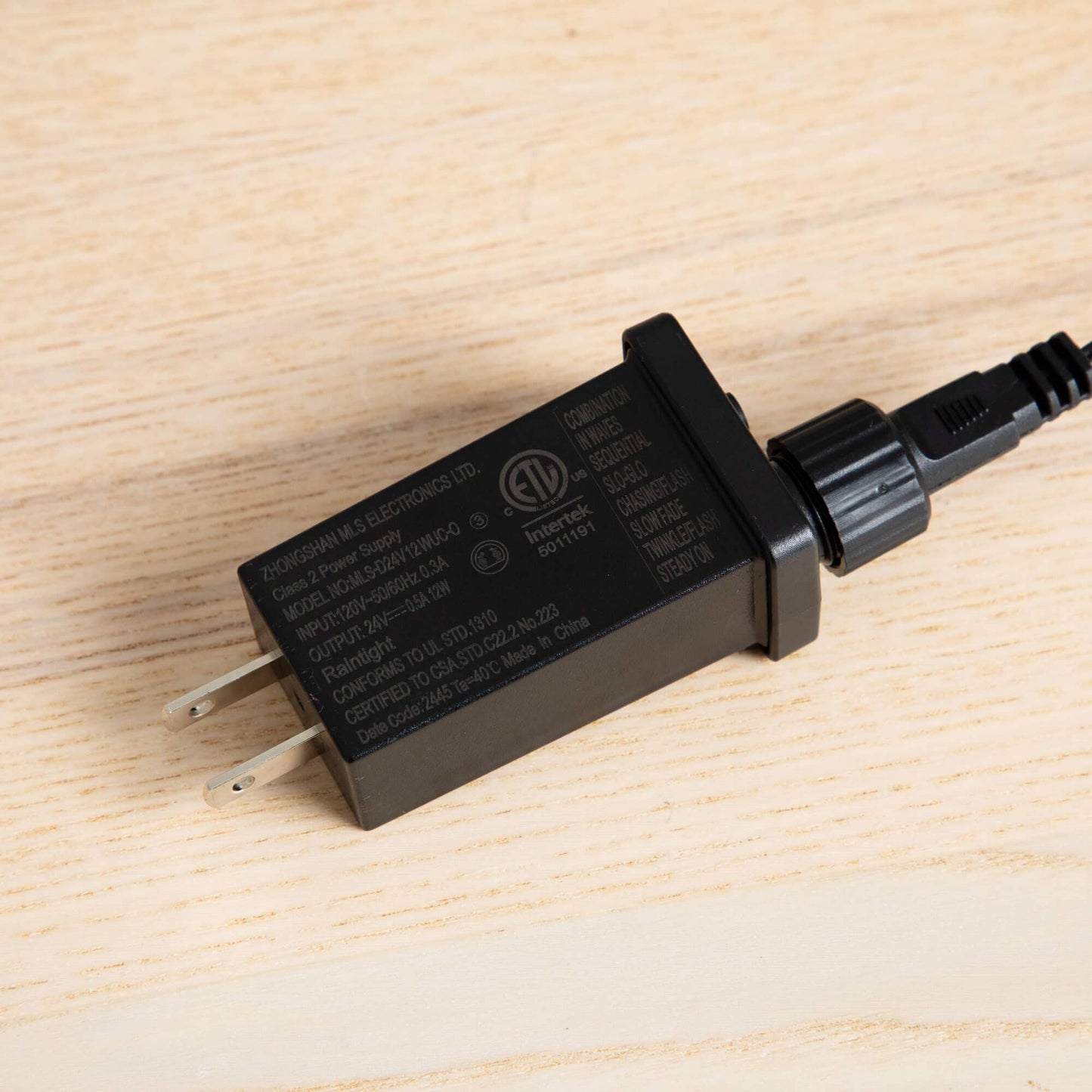 Black LED transformer for pre-lit tree, power adapter with prongs visible on wooden surface on Tampa Home & Garden Store