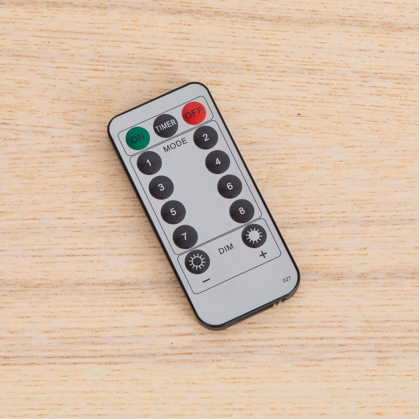 Remote control with many black buttons placed on light wood surface on Tampa Home & Garden Store