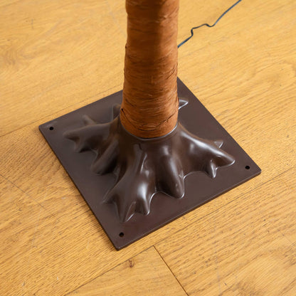 Artificial tree trunk wrapped in brown protective wrap on a dark plastic base with a cord visible on Tampa Home & Garden Store