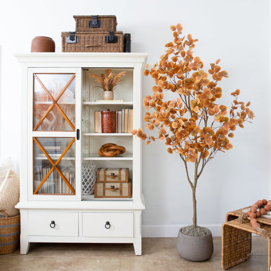 7 ft artificial autumn eucalyptus tree with orange leaves beside a white cabinet on Tampa Home & Garden Store