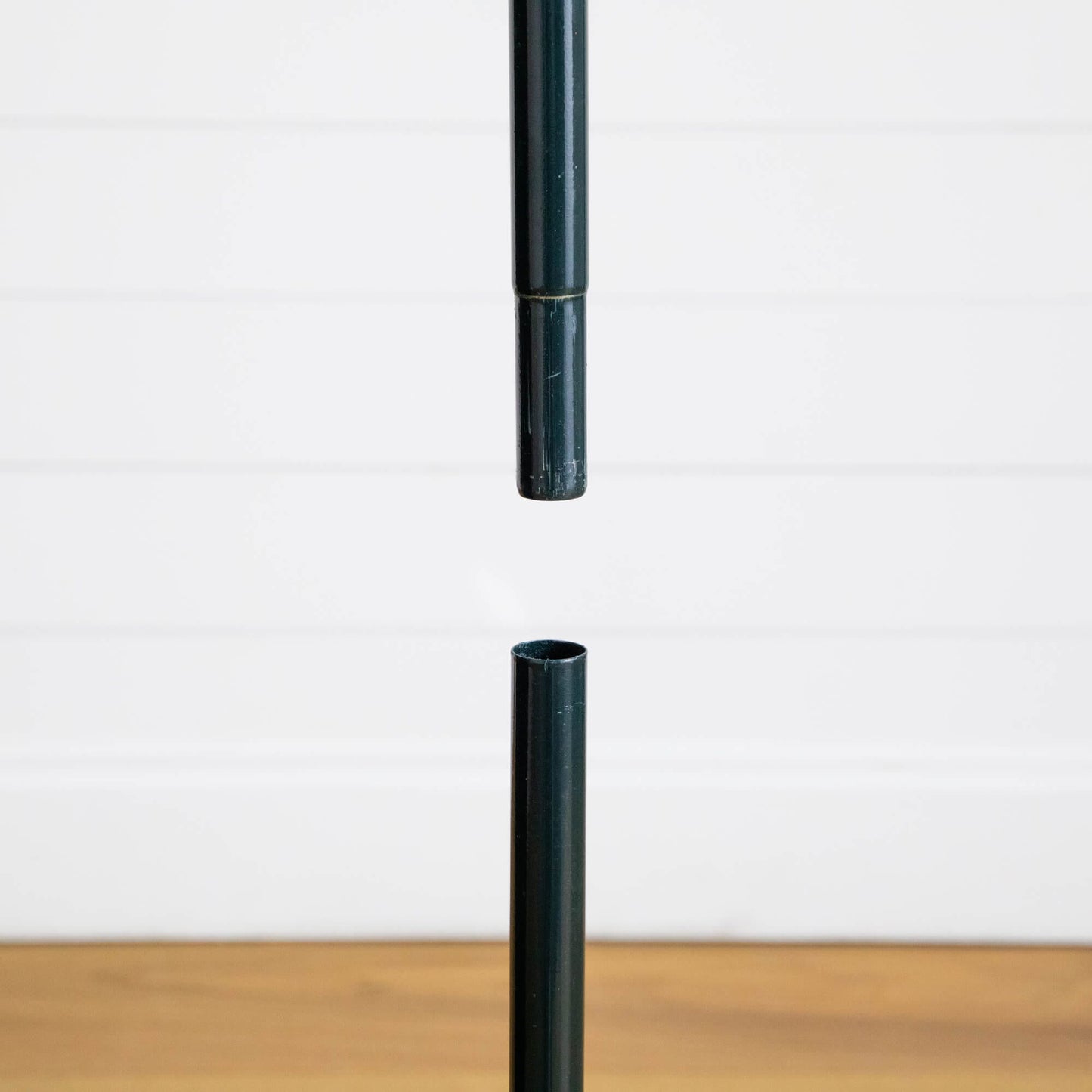 Dark green pole segments for Nearly Natural pop up tree against white wall on Tampa Home & Garden Store