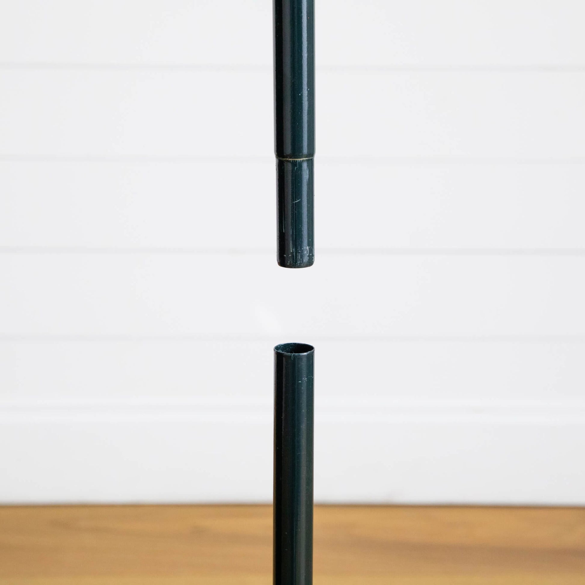 Dark green pole segments for Nearly Natural pop up tree against white wall on Tampa Home & Garden Store