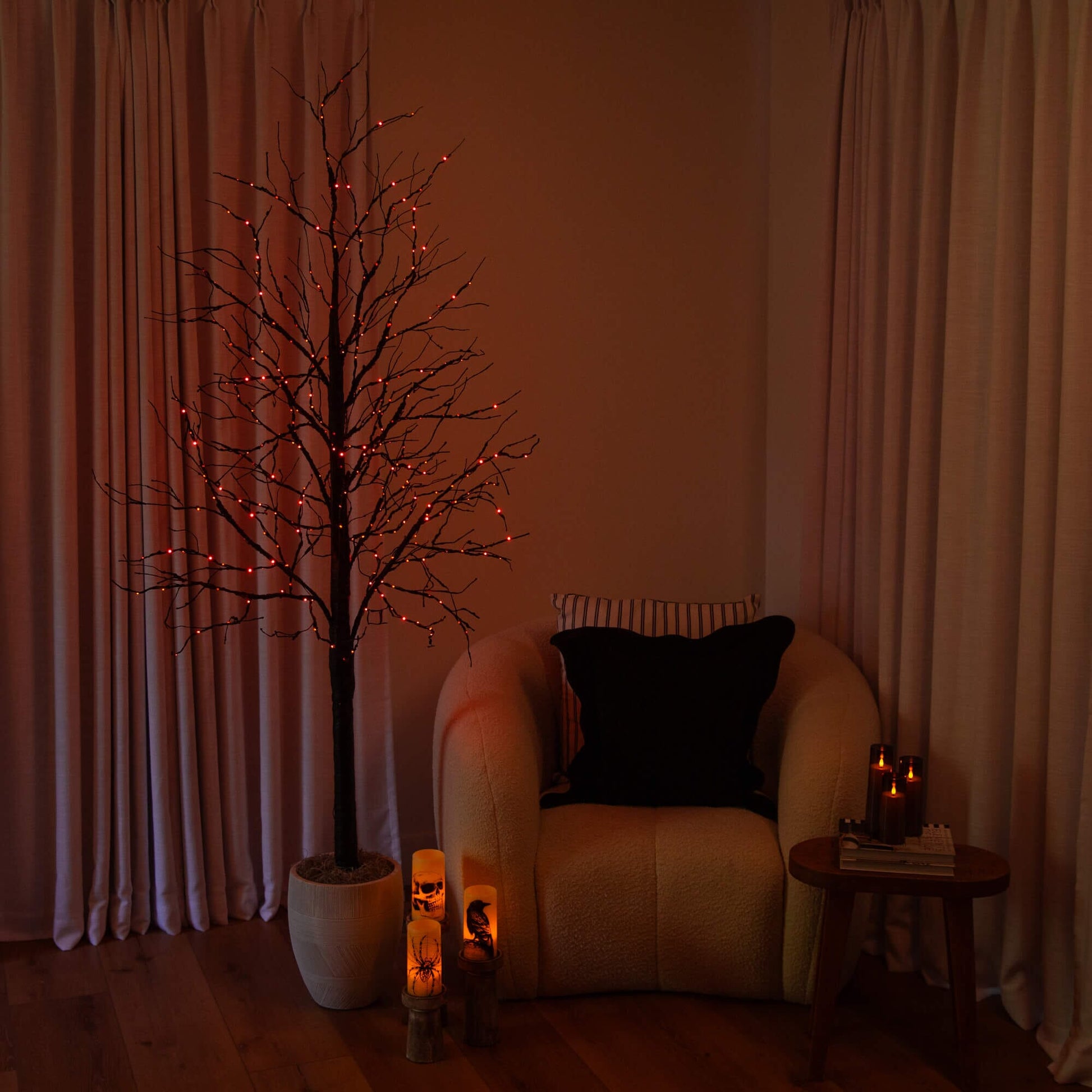 7' Pre-Lit Halloween Black Twig Tree with orange and purple LEDs in a white pot beside sofa on Tampa Home & Garden Store