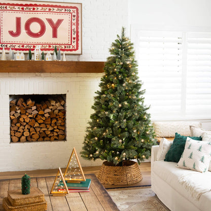 Nearly Natural 7.5' artificial Christmas tree with 450 warm white globe bulbs and LED lights, placed in a cozy living room beside a white brick fireplace on Tampa Home & Garden Store