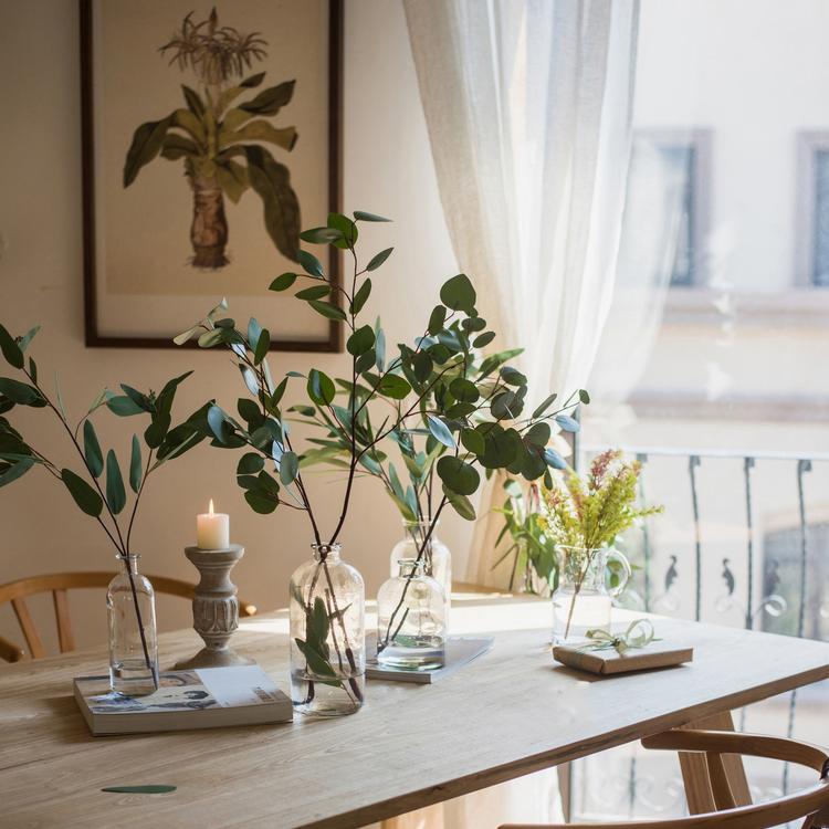 Artificial eucalyptus leaves in clear glass bottles on a wooden table RusticReach flora on Tampa Home & Garden Store