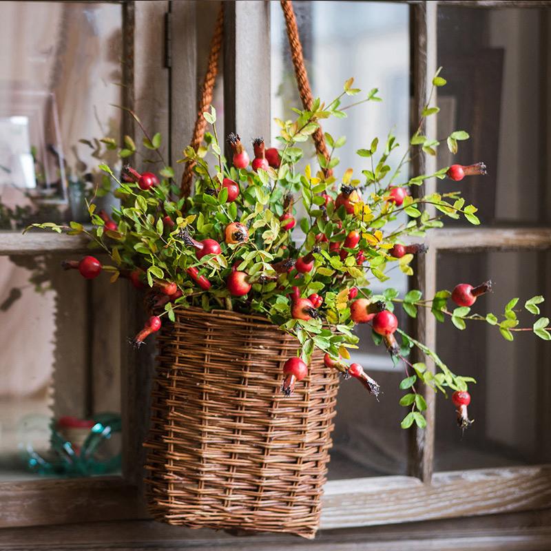 Artificial pomegranate fruit stem with red berries and green foliage in a woven hanging basket on Tampa Home & Garden Store