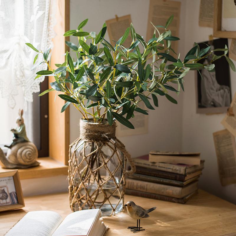 Artificial Faux Olive Leaf Stem in a glass vase with twine-wrapped netting on a wooden desk on Tampa Home & Garden Store