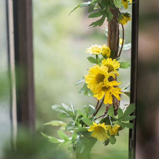 Artificial Sunflower Vine with yellow blooms and green leaves on a 67 inch stem by window on Tampa Home & Garden Store