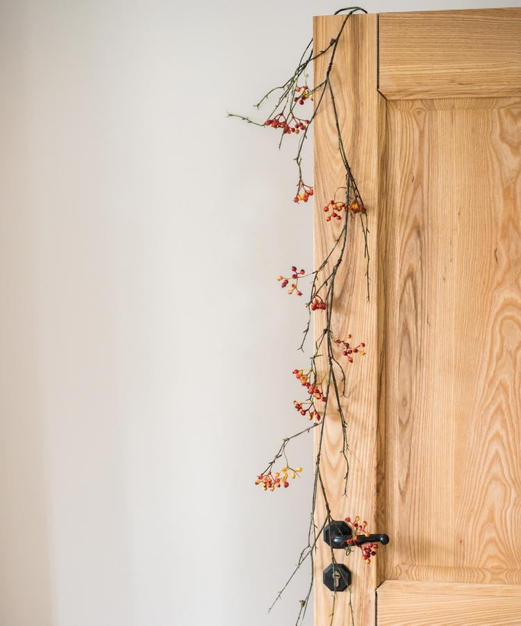 Artificial Orange Faux Berry Vine by RusticReach, 39in long, drapes over a wooden door on Tampa Home & Garden Store