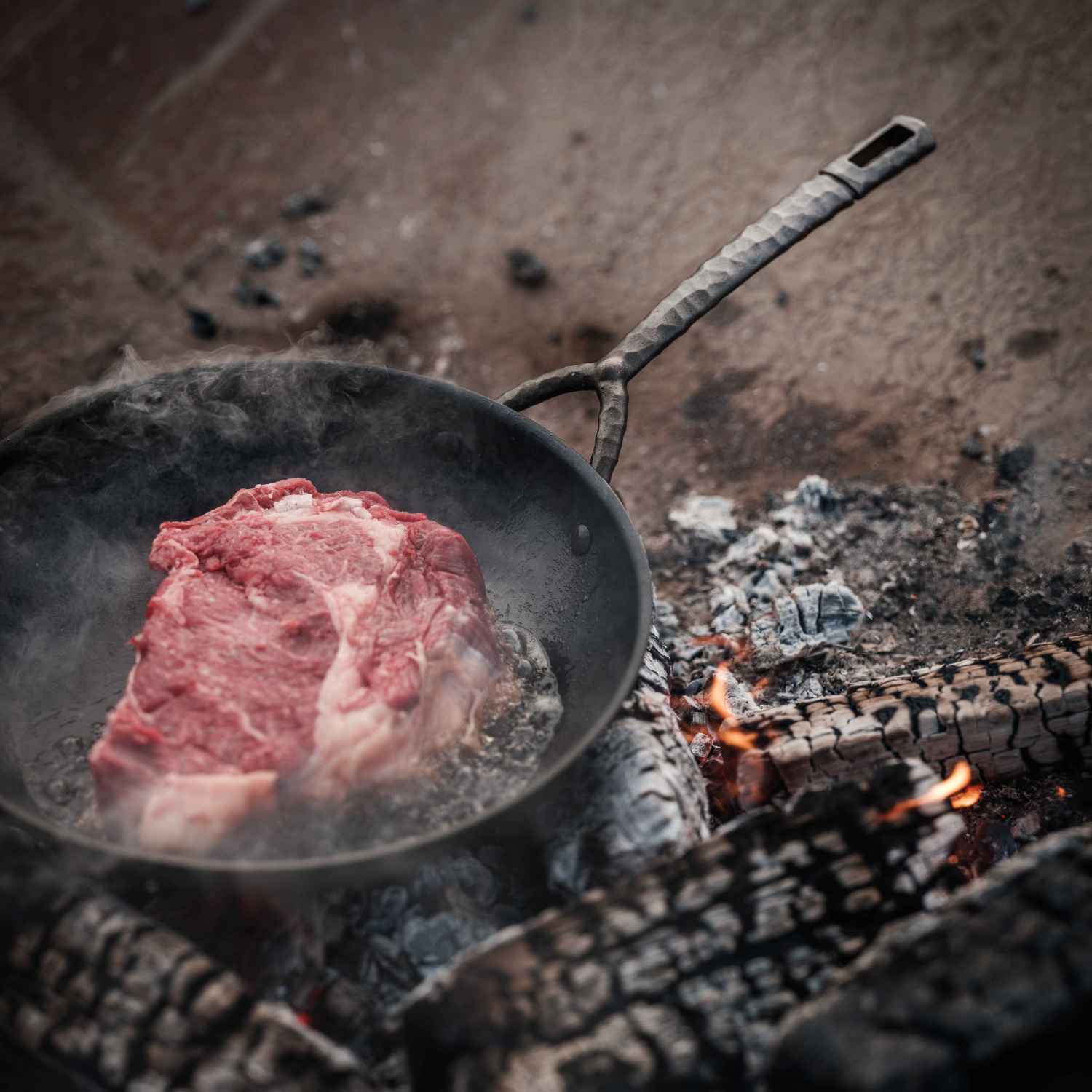 Carbon Steel Frying Pan by Alva Cookware with hammered handle cooking steak over open flame on Tampa Home & Garden Store