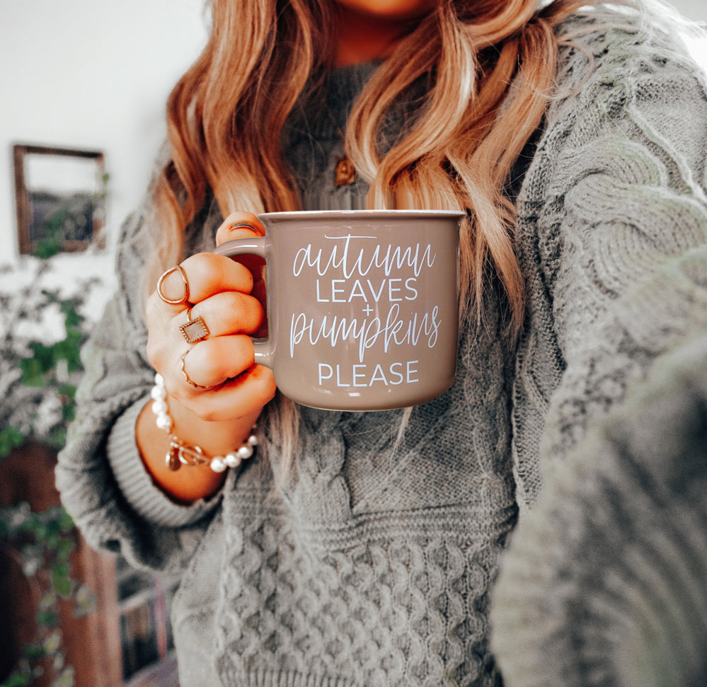 Autumn Leaves coffee mug by Gia Roma in taupe ceramic with white script held in a knit sweater on Tampa Home & Garden Store
