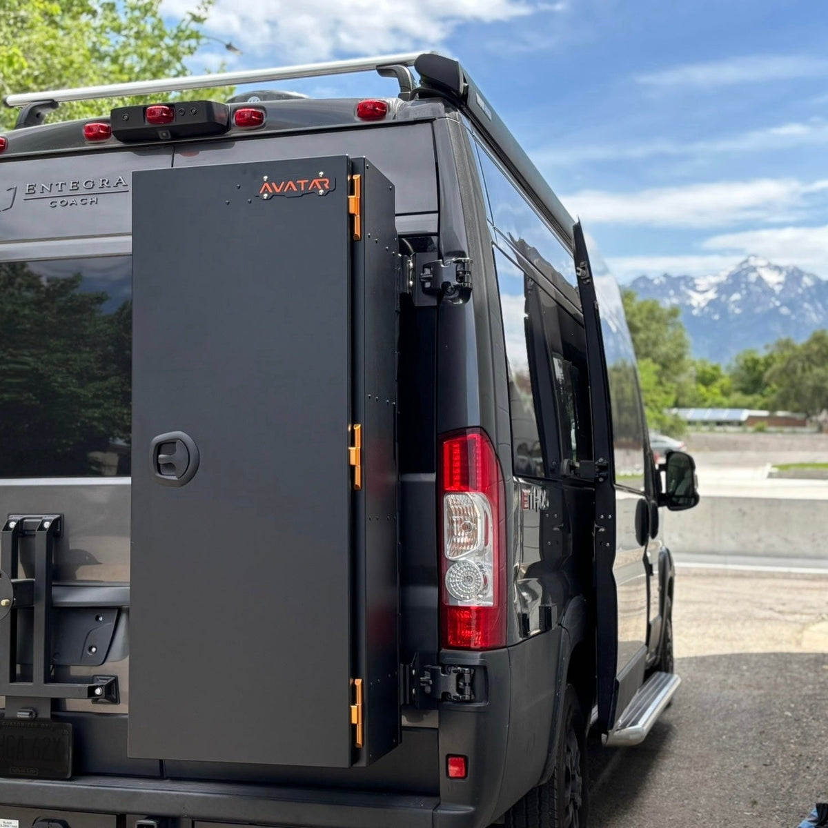 Avatar Caddie Storage Box mounted on back of a dark SUV; gray metal box with orange latches on Tampa Home & Garden Store