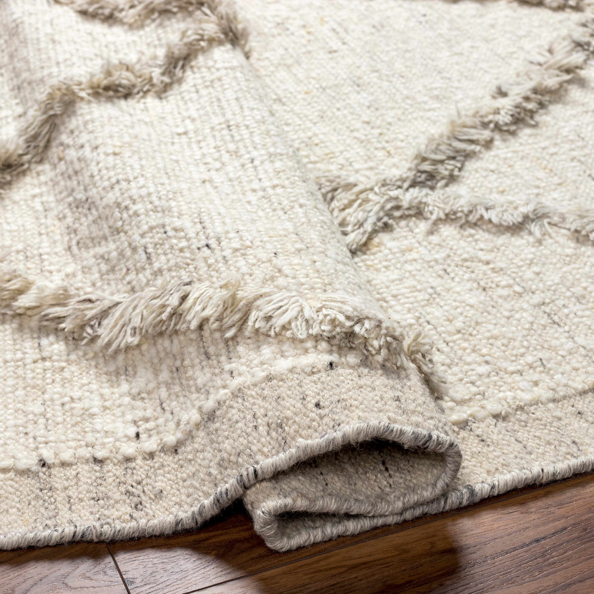 Awen hand-knotted wool area rug ivory with fringe, Boutique Rugs, stacked on wood floor on Tampa Home & Garden Store