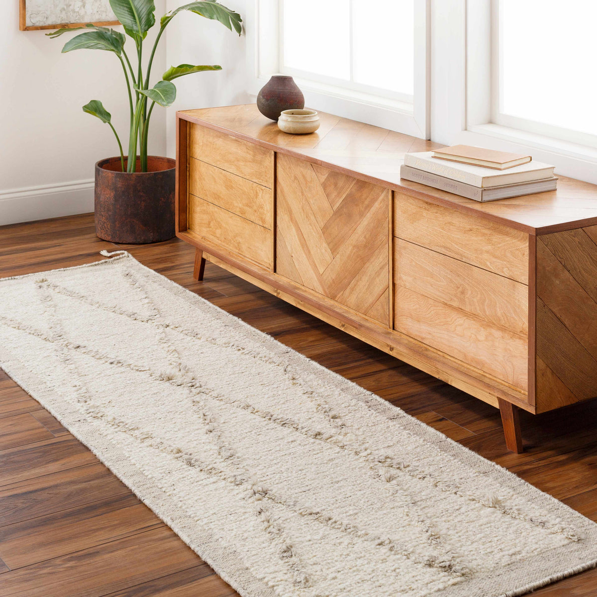 Awen Hand Knotted Wool Area Rug in cream, placed beside a wooden console with plants on Tampa Home & Garden Store