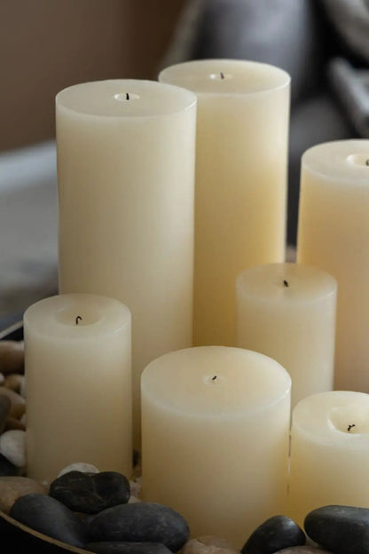 Unscented soy wax pillar candles, cream color, set of 2, arranged among decorative stones on Tampa Home & Garden Store