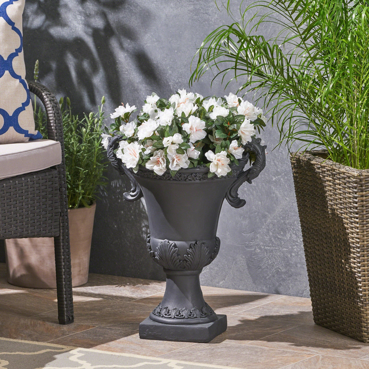 Delphine Urn Planter, black ornate pedestal with scroll handles and white blooming flowers on Tampa Home & Garden Store