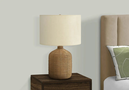 Table lamp with woven rattan base and beige fabric shade on a dark wood nightstand on Tampa Home & Garden Store