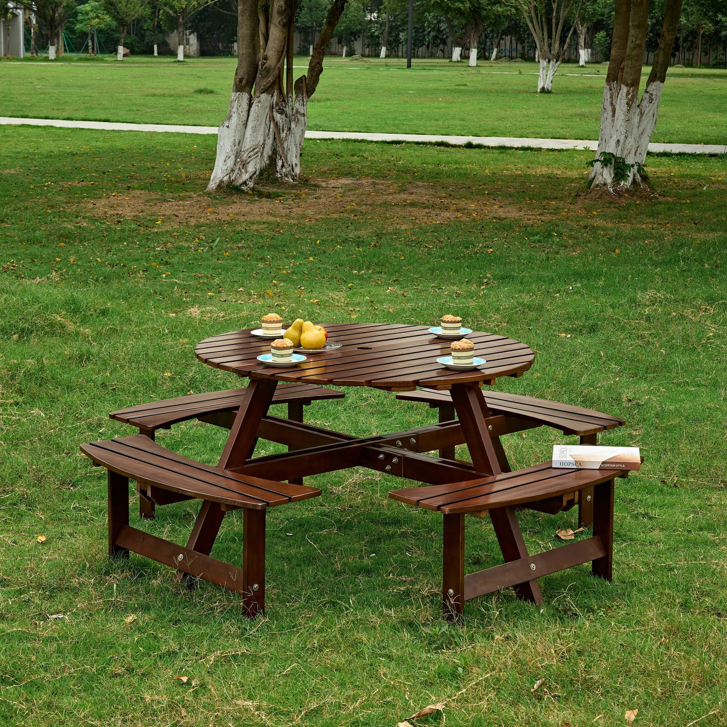 Outdoor 8-person round picnic table with built-in benches in brown wood on a lawn on Tampa Home & Garden Store