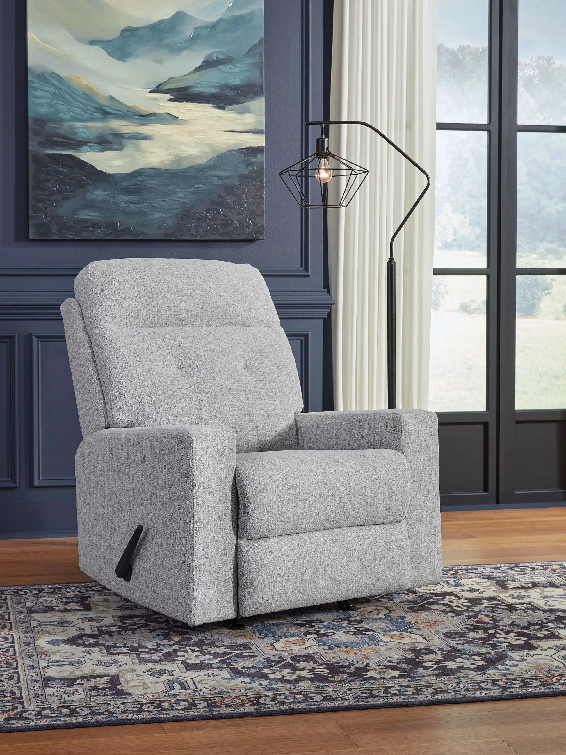Rocker recliner in stone fabric placed against navy paneled walls with a modern geometric lamp on Tampa Home & Garden Store
