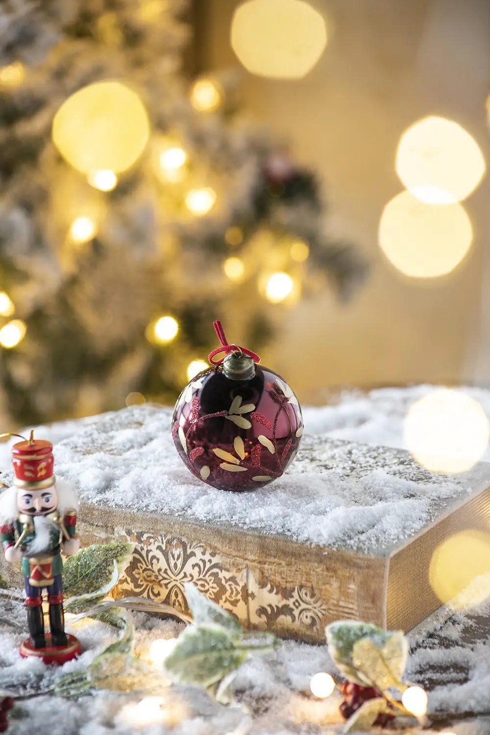 Glass Christmas ball ornament burgundy with gold leaf accents on snowy display on Tampa Home & Garden Store
