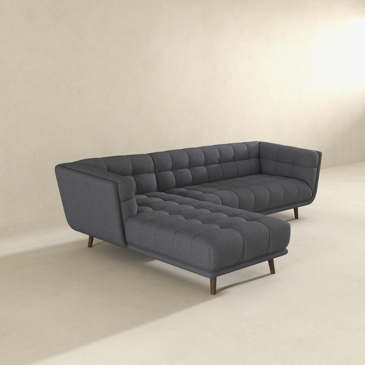 Mid-century tufted L-shaped sofa in dark gray fabric with wood legs on Tampa Home & Garden Store