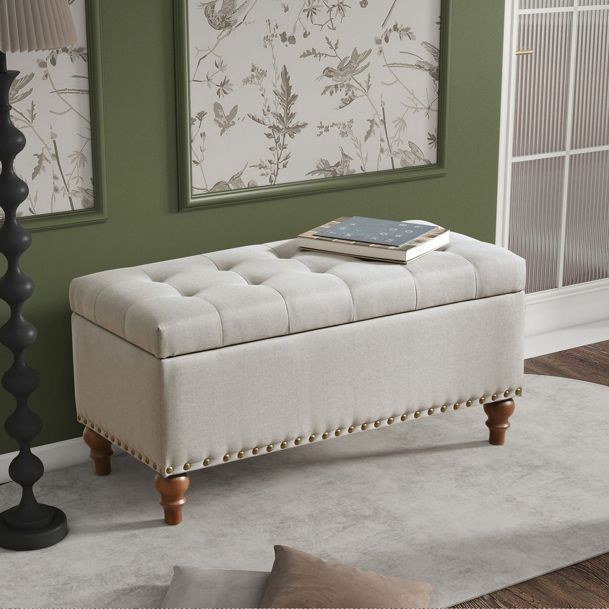 Upholstered storage ottoman with rivet trim in beige fabric, tufted lid, bun feet on Tampa Home & Garden Store