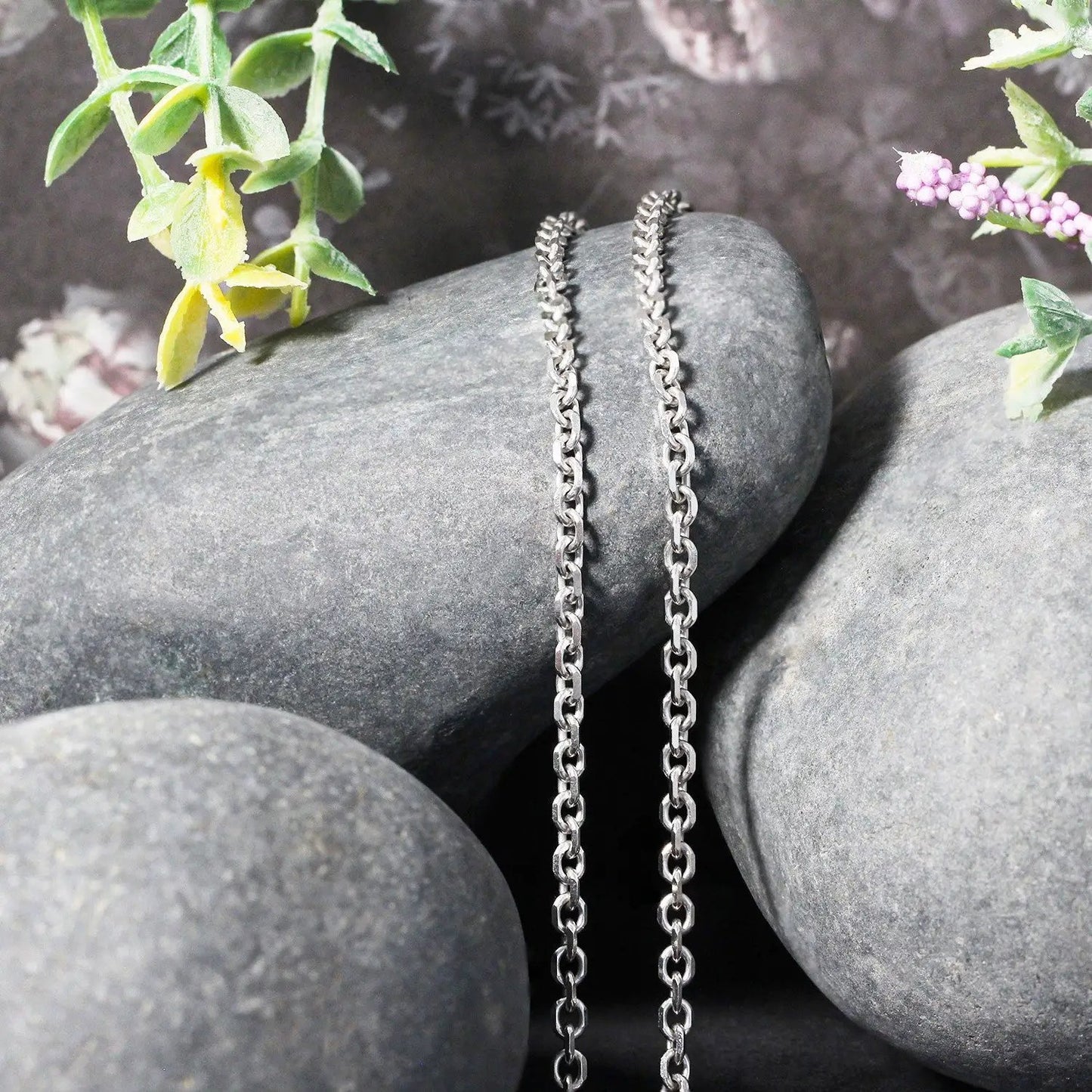 Two 14k white gold diamond-cut cable link chains draped over smooth rocks on Tampa Home & Garden Store